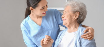 A nurse/home health aide is assisting an elderly patient