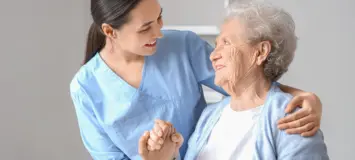 A nurse/home health aide is assisting an elderly patient