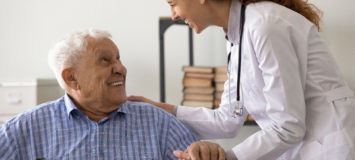 Friendly female caregiver give support older male with severe diagnosis