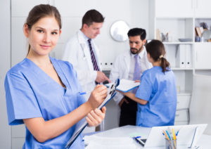 Young doctor assistant standing in medical office noting prescriptions