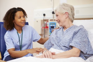 Nurse sitting by female patient bedside